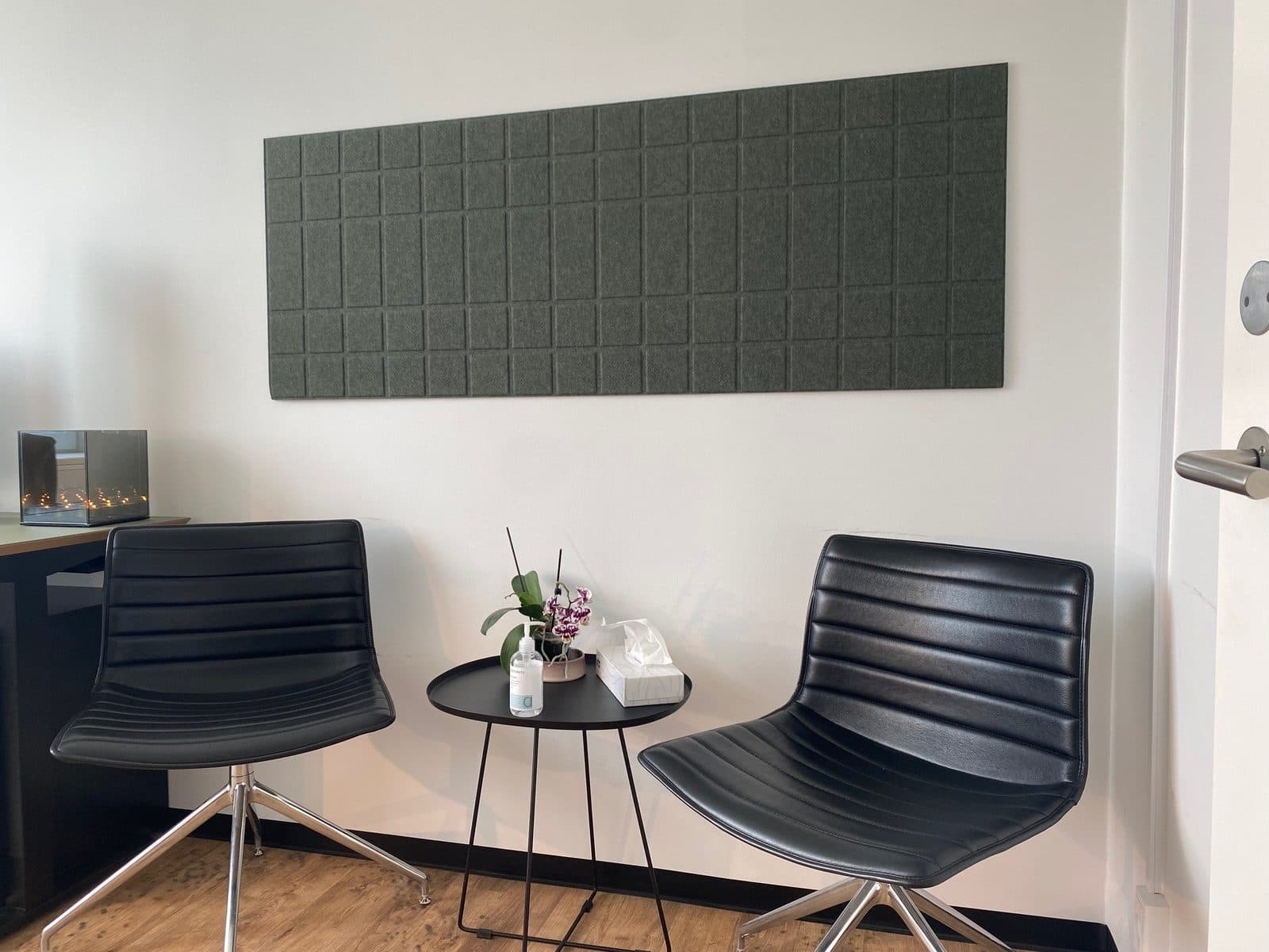 Konsultationsrum hos Privat Psykiatrisk Center Aalborg med to læderstole, bord og grøn akustikpanel